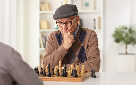 An older man playing chess, concentrating on the board