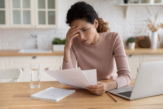 A woman at her desk resting her head in her hand, looking tired in front of her computer