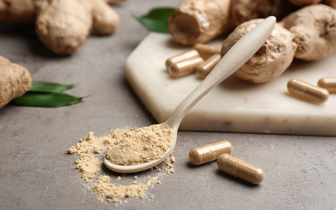 A spoonful of brown powder beside a few capsules and dried roots